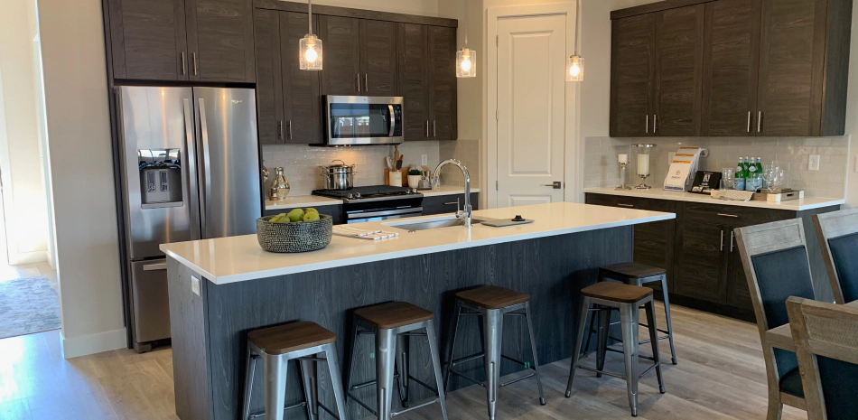 greyish beige kitchen sink with brown cabinets and grey chairs with a white countertop